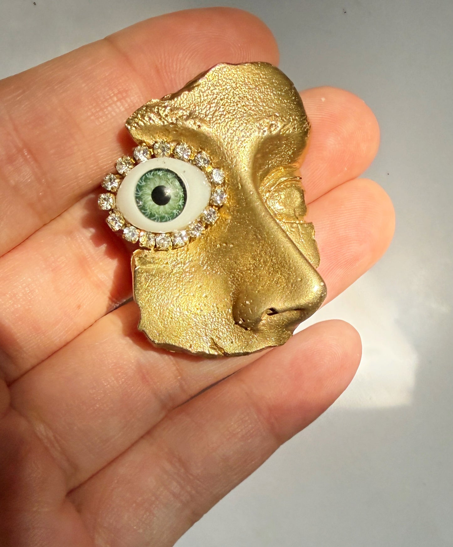 Gilded artifact face brooch